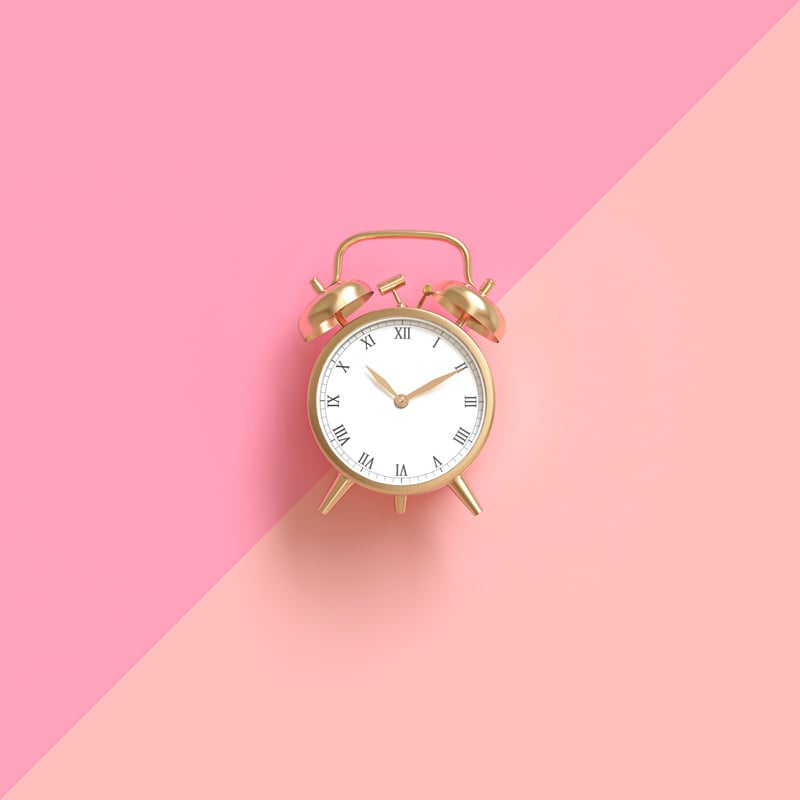 Gold Alarm Clock on a Two-Tone Pink Background.